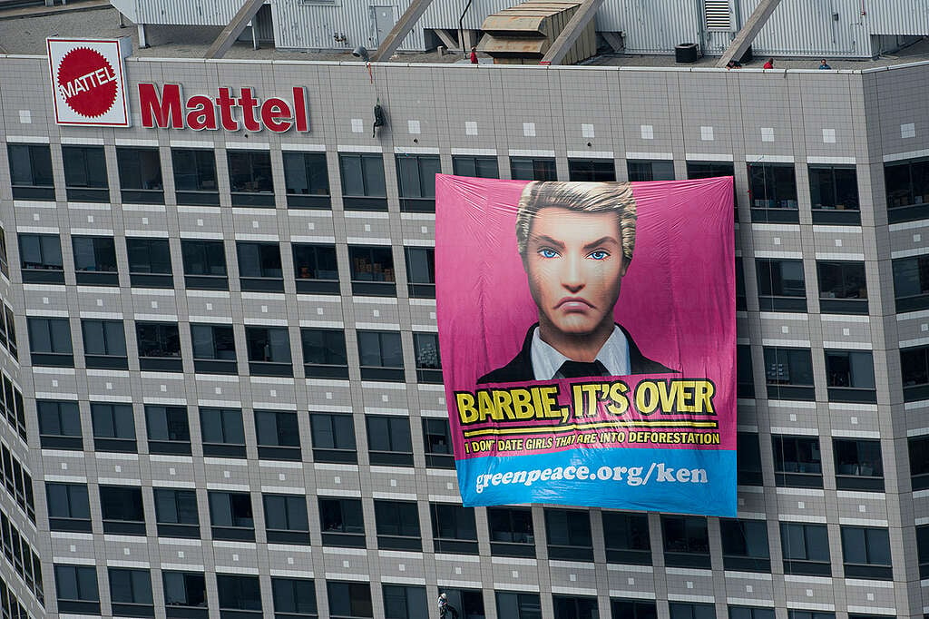 Banner of a Ken Doll saying "Barbie it's Over" hanging from a Mattel corporate building