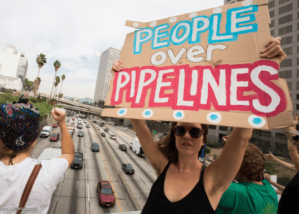 Activist holding a sign that says 'people over pipelines'